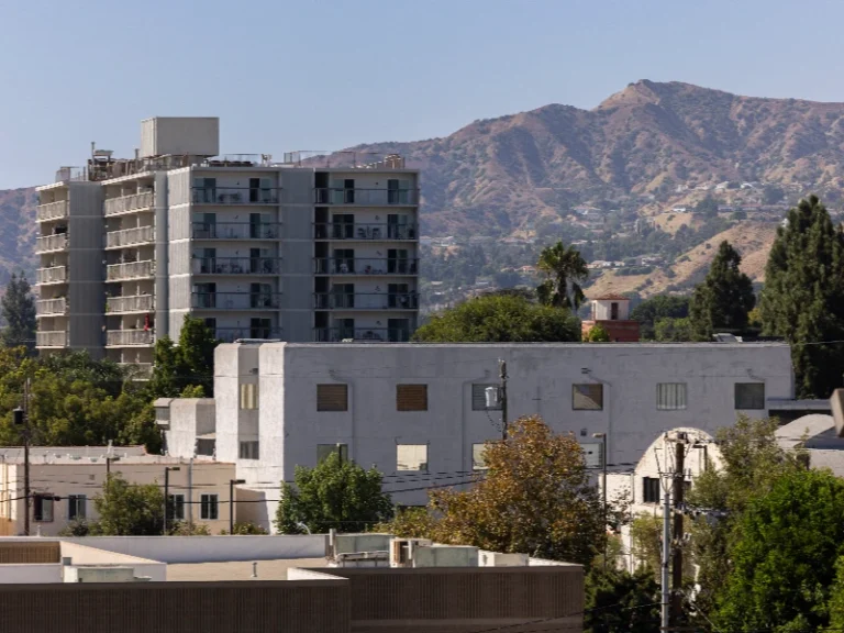 Apartment buildings and trees with a mountain range in the background under a clear sky. Showcases that the company does flood water restoration service in Burbank CA.