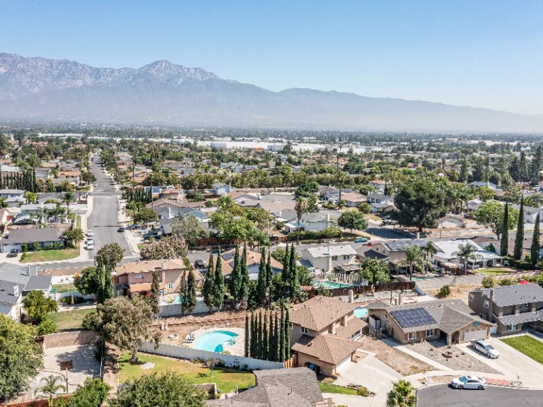 Suburban neighborhood with houses, swimming pools, and mountains in the background under a clear sky. Showcases that the company has San Fernando CA water extraction service offerings.